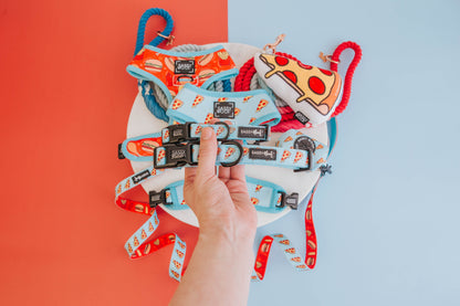 Sassy Woof dog collar featuring a vibrant One Hot Pupperoni design with colorful pepper illustrations on a black background.