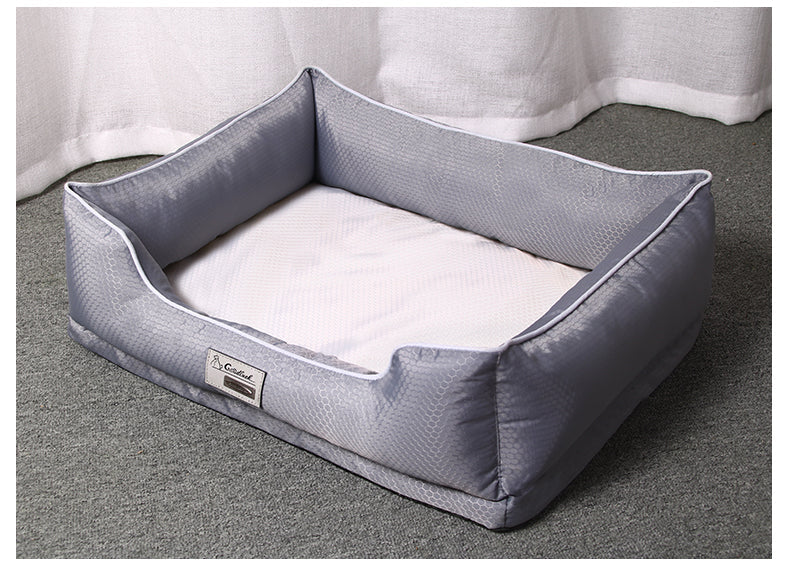 Grey rectangular dog bed with white piping and supportive bolster walls on a textured floor.