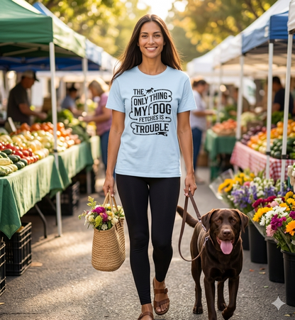 An elegant woman wearing a light blue 'The Only Thing My Dog Fetches Is Trouble' graphic t-shirt while walking her chocolate Labrador at a Nashville farmers market.