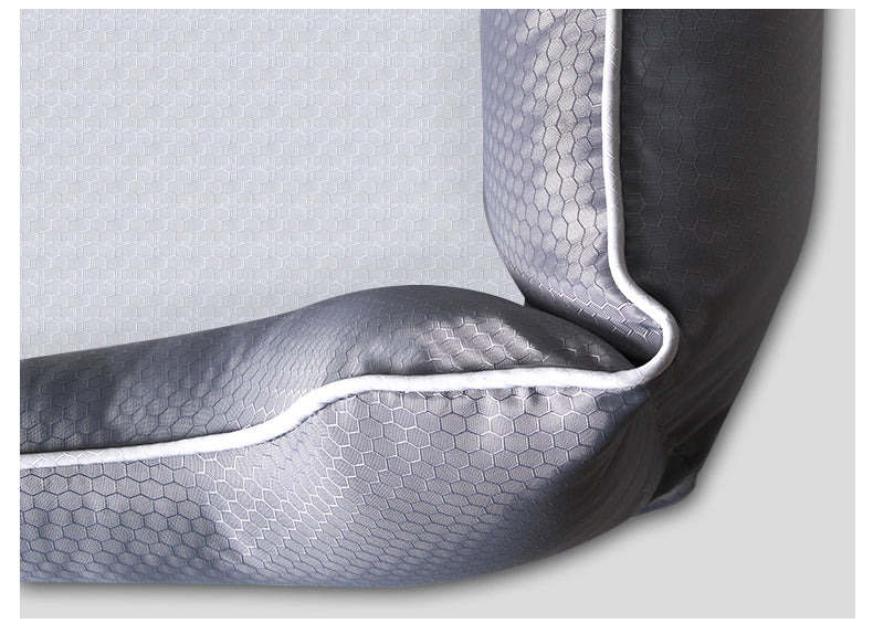 Close-up view of a grey pet bed featuring a durable hexagonal pattern fabric and clean white piping trim.