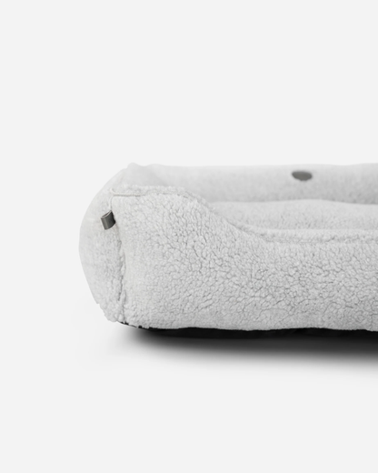 Chester and Lee luxury furry sleeper dog bed in gray with a small black poodle sitting inside, styled in a modern living room.
